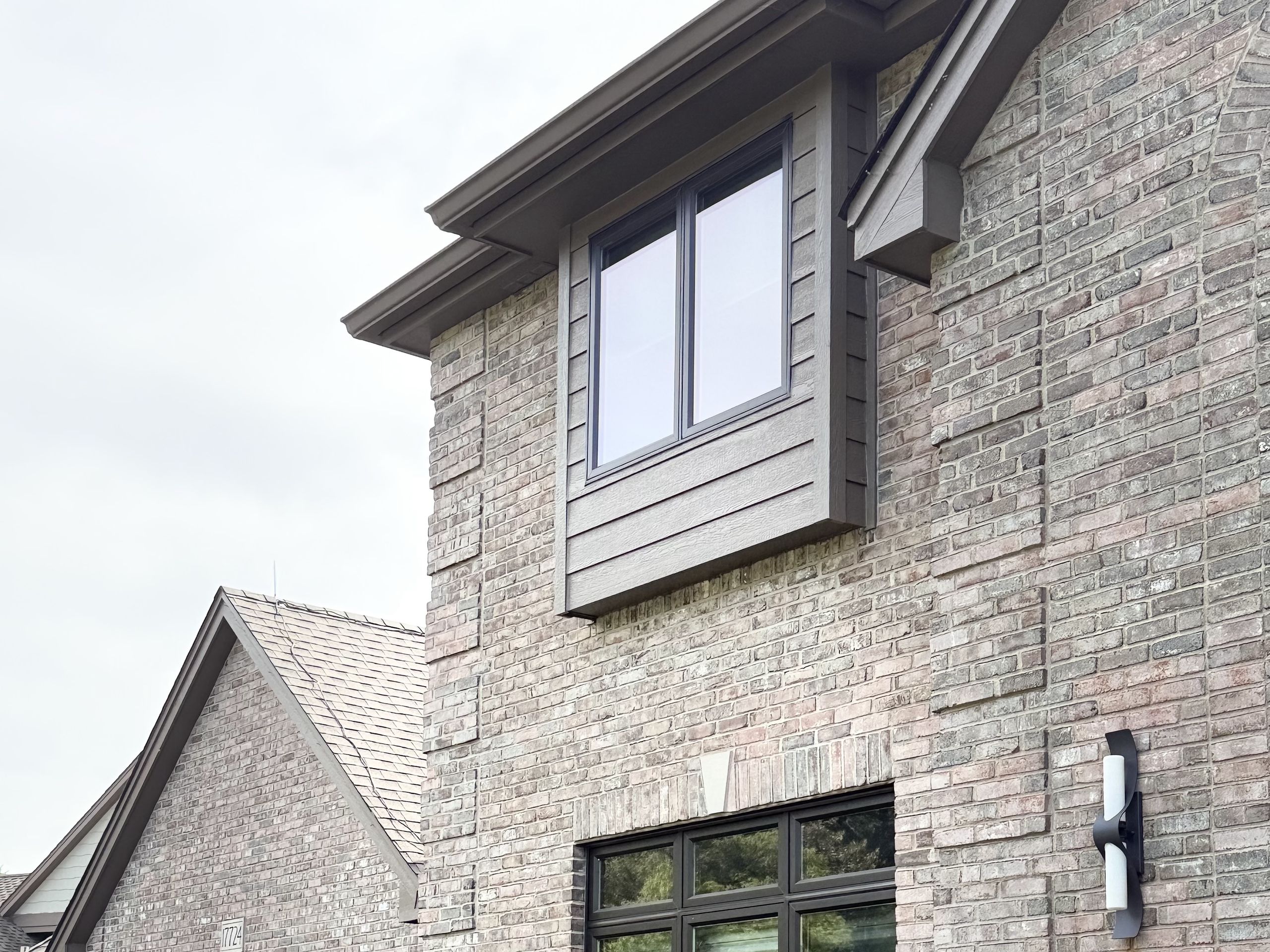 Two-story brick elevation with a sided bay window above and a tall window below