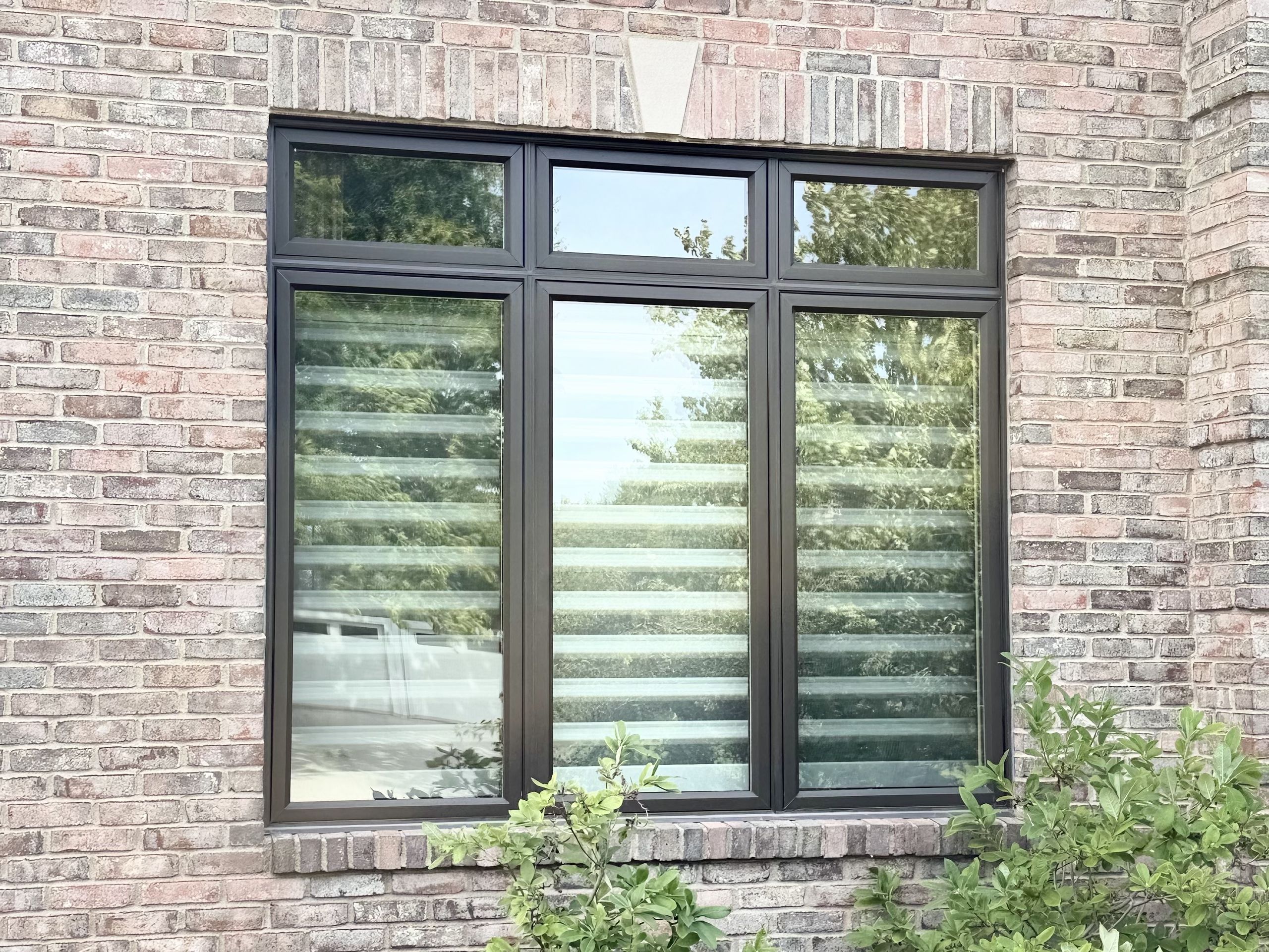 Three-wide replacement window unit in a brick wall above a flower bed