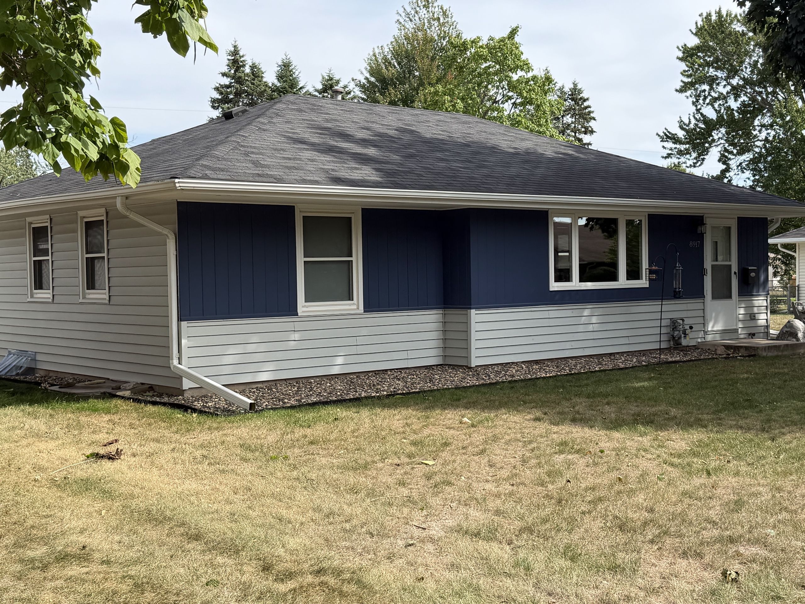 Rambler finished in blue board-and-batten and white lap Siding