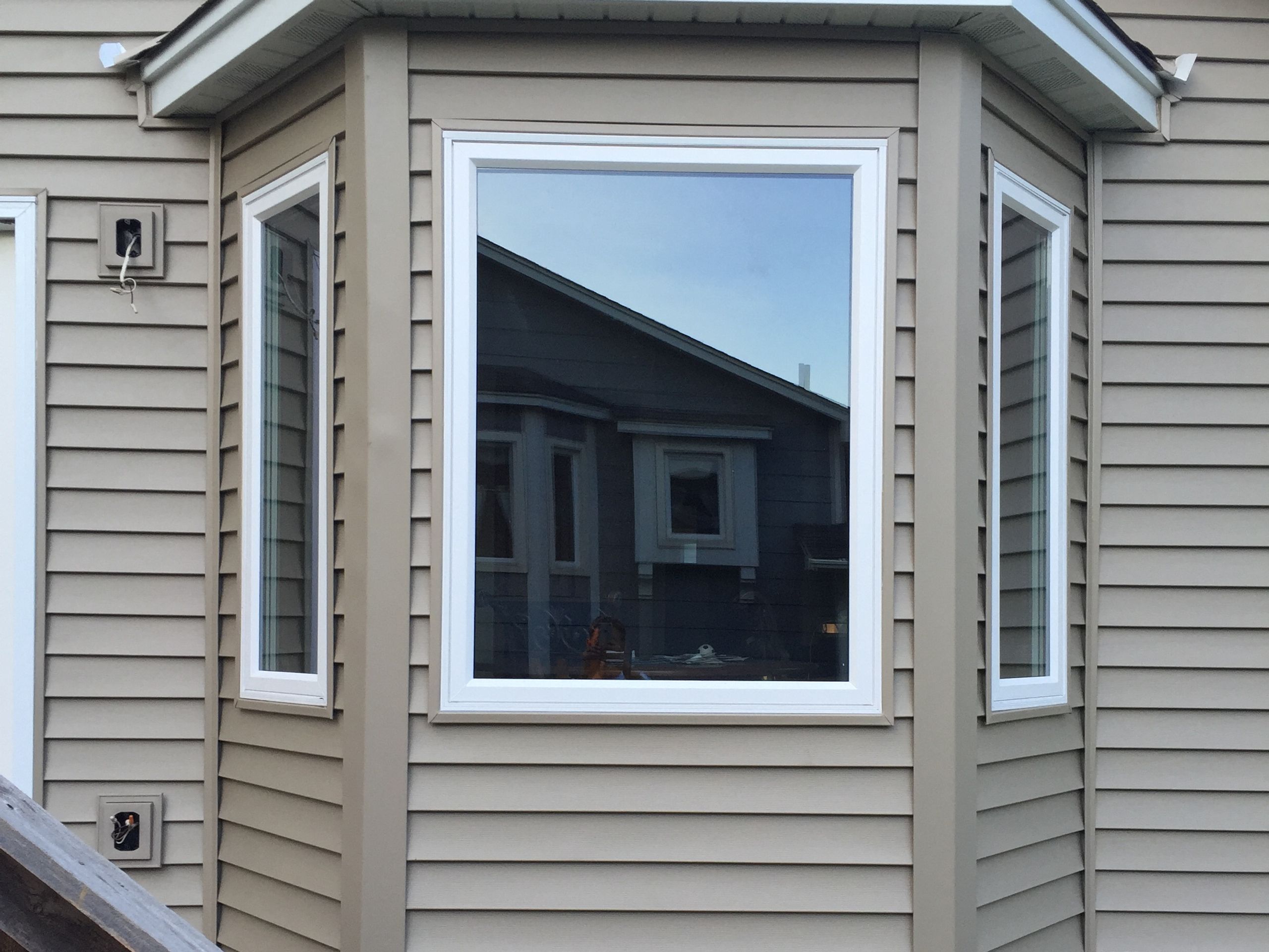 Tan vinyl lap Siding wrapped around a bay window bump-out