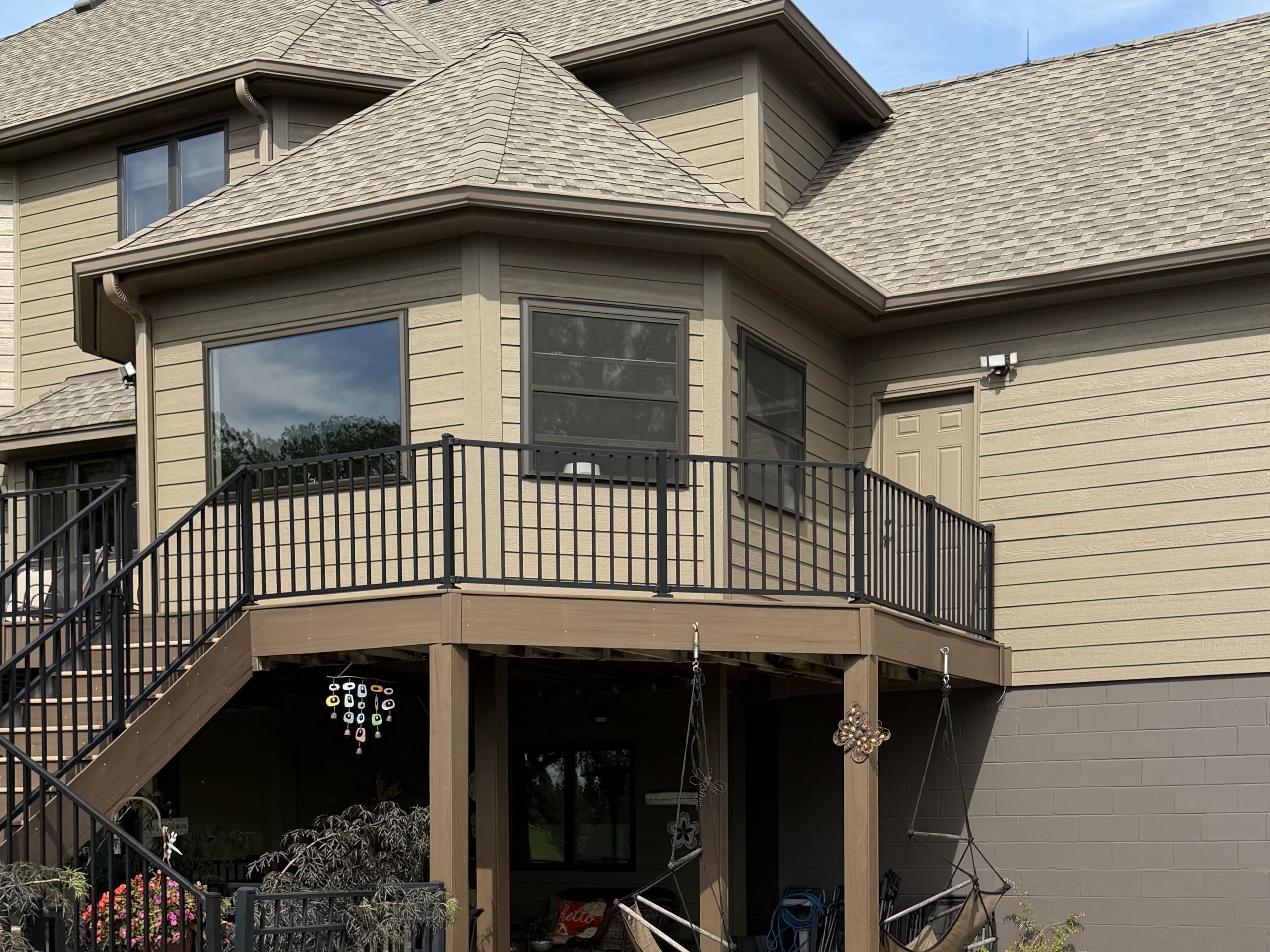 Pool and patio below the deck of a re-sided two-story home
