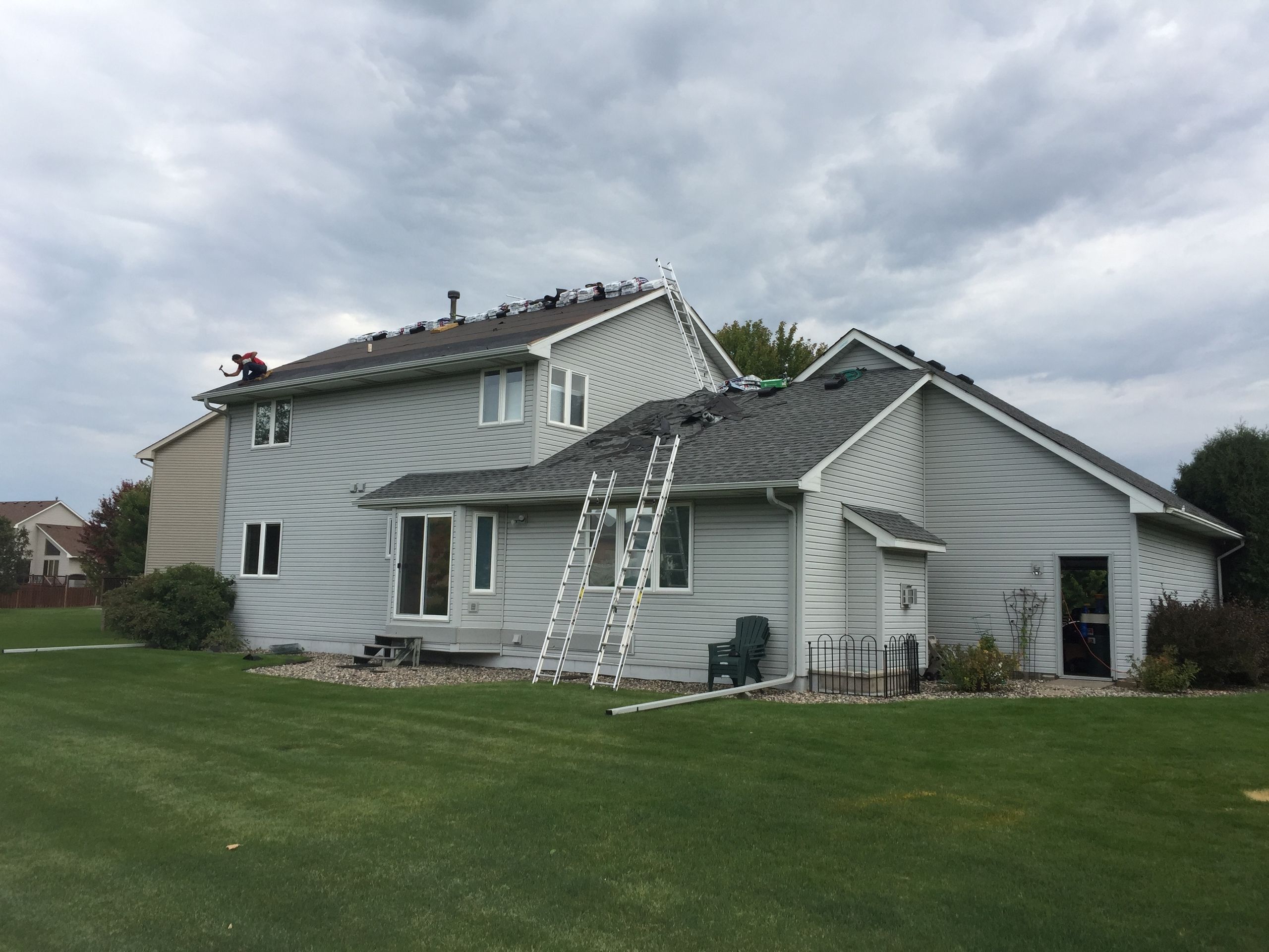 Shingle bundles staged along the ridge during a re-roof on a two-story home