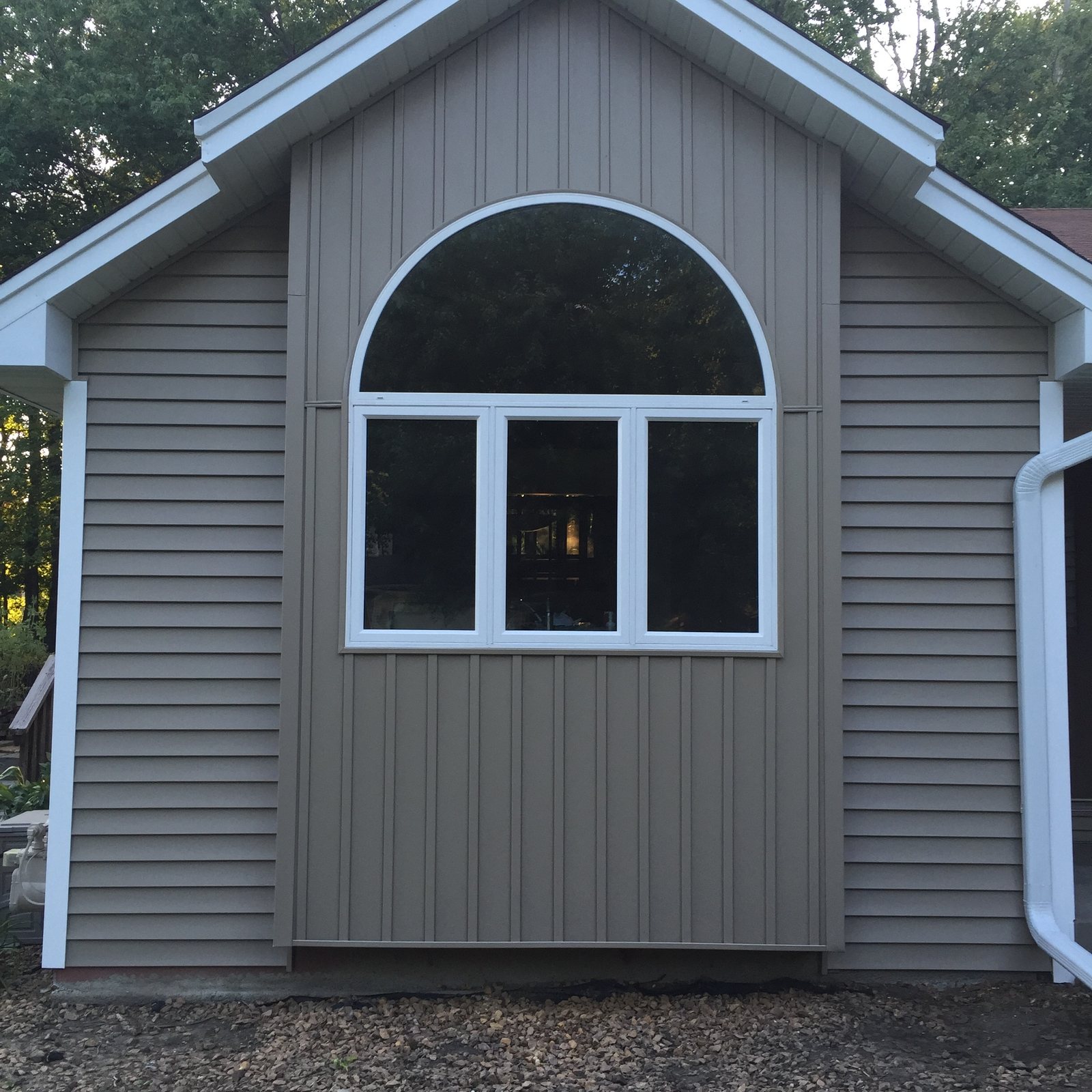 Arched window centered in a gray board-and-batten gable