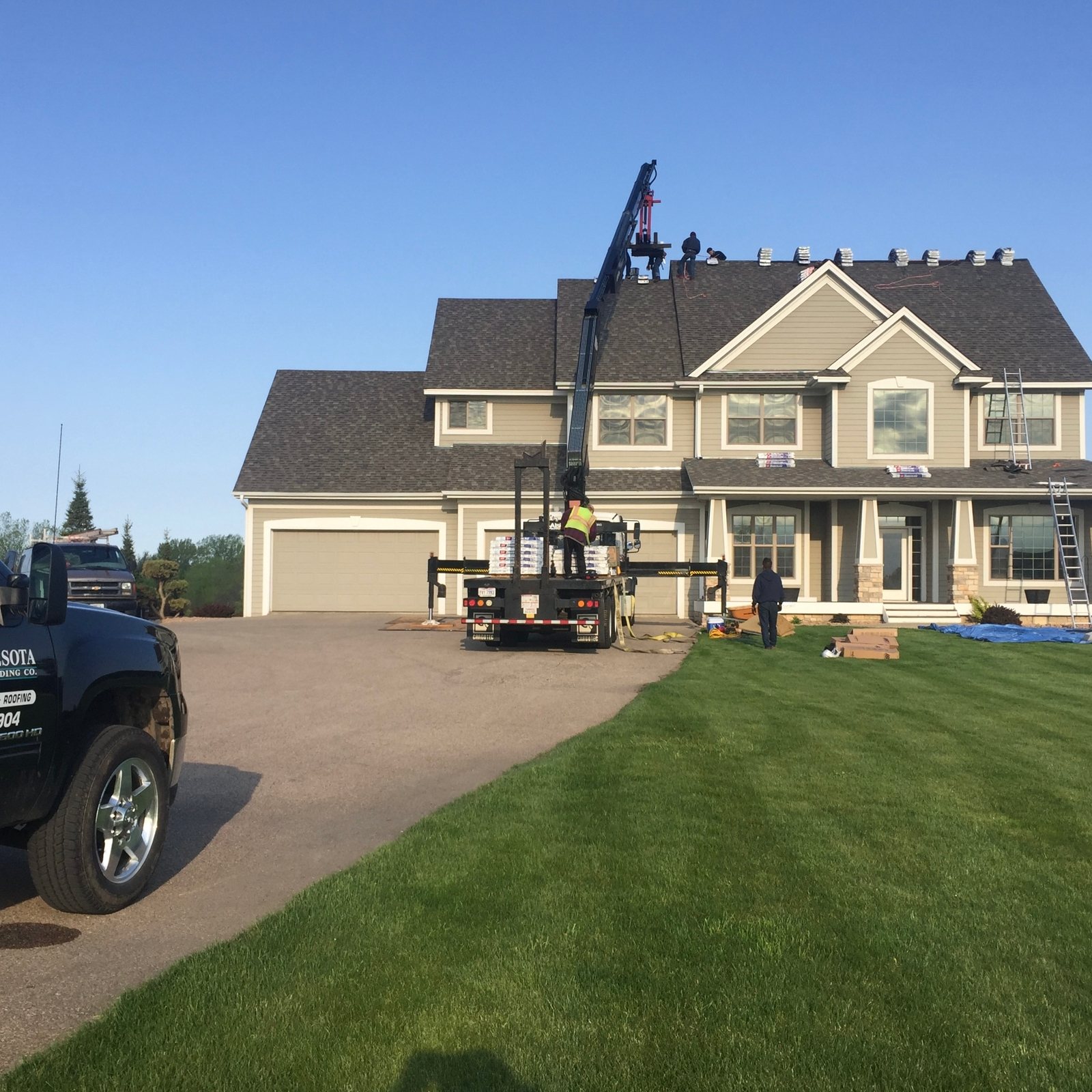 Boom lift at the front of a tan two-story home