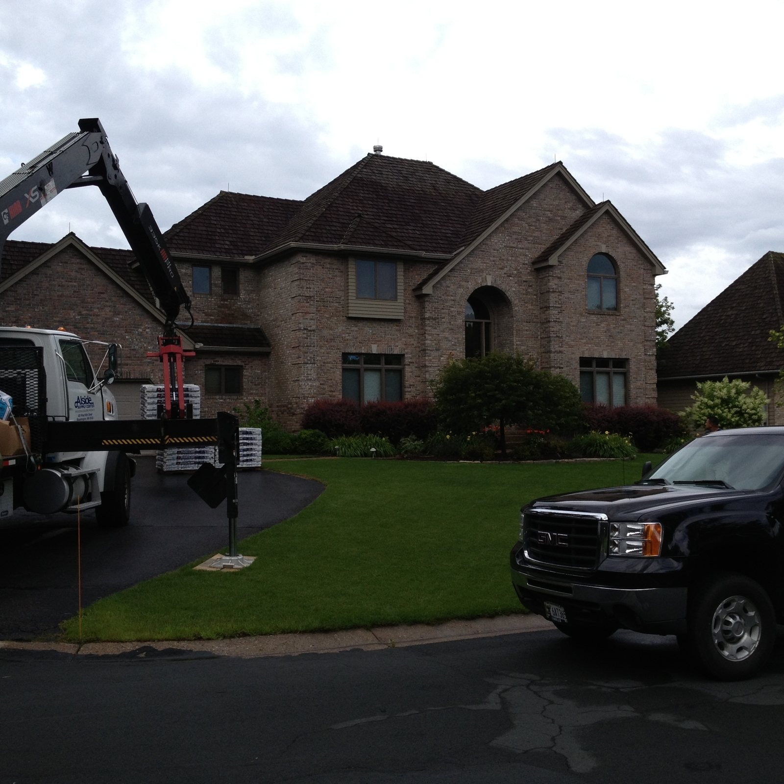 Delivery truck unloading beside a brick two-story home
