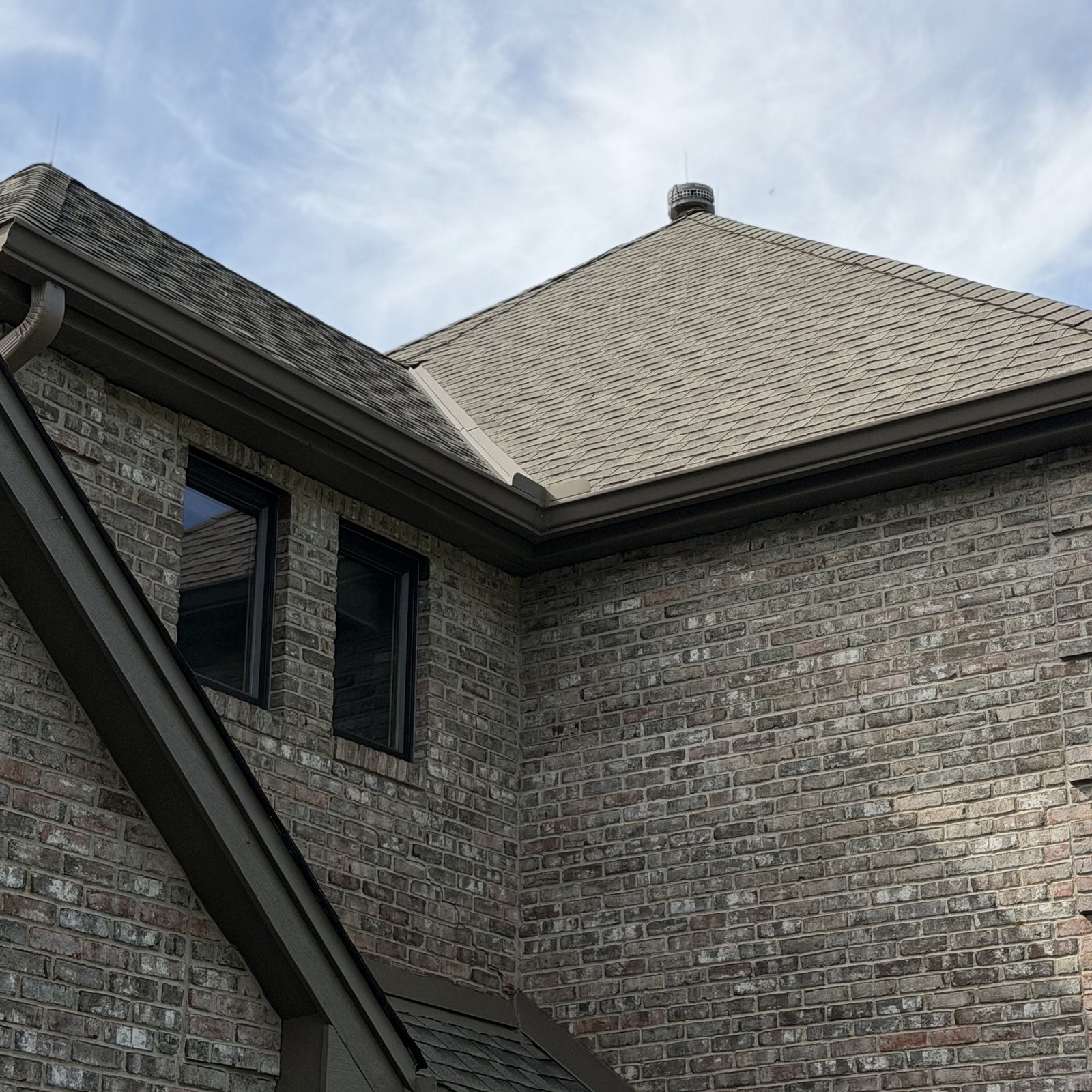 Dark Gutter wrapping a hip roofline over brick