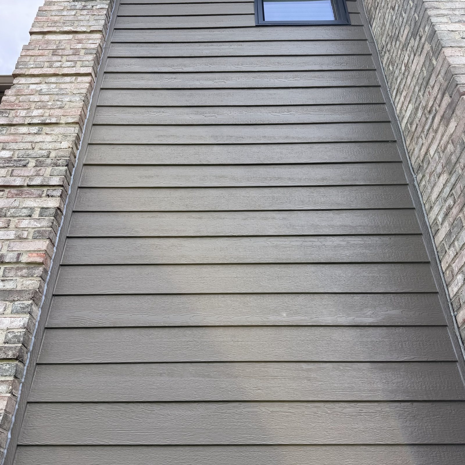 New lap Siding running up a wall beside brick
