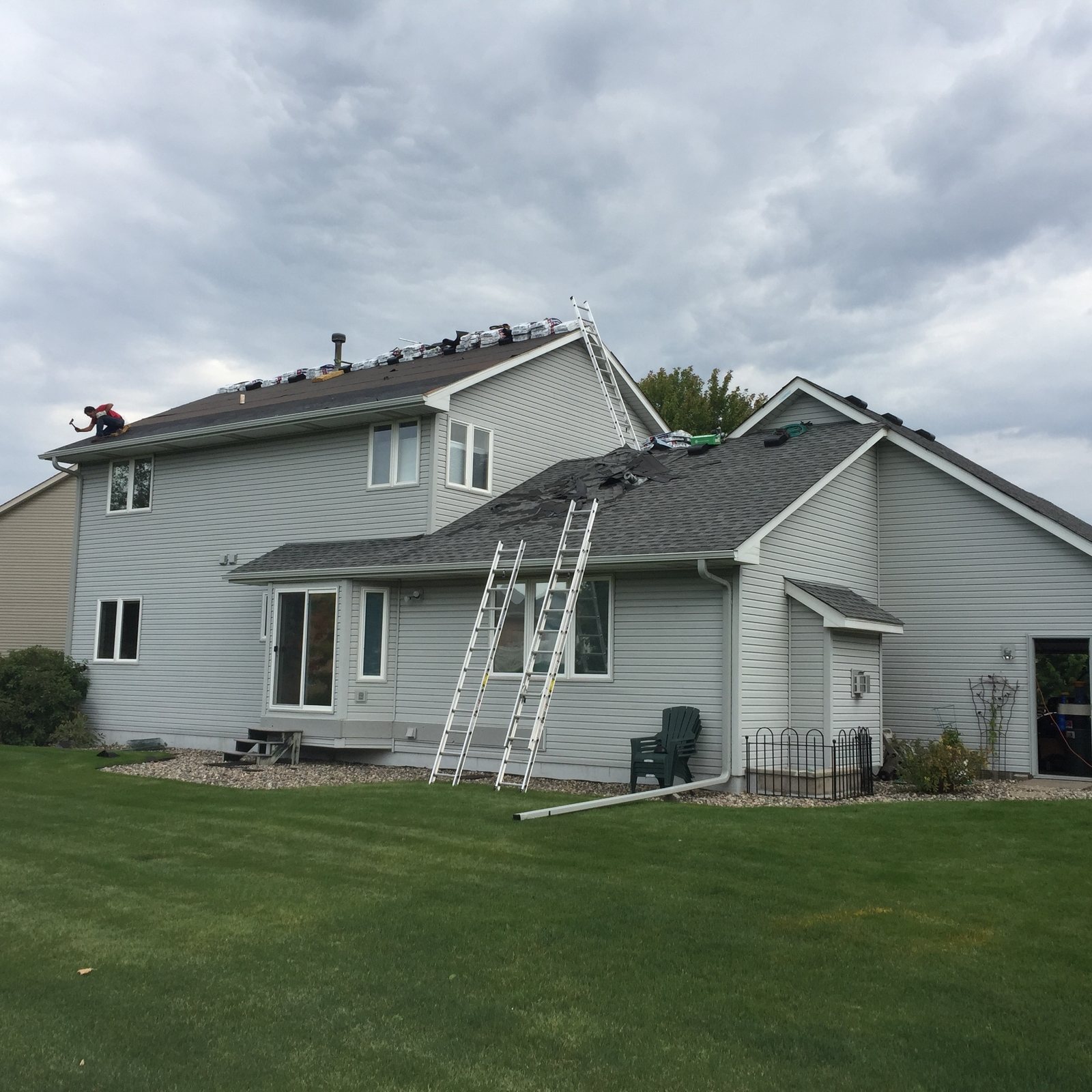 Ladders against a two-story home midway through new Siding