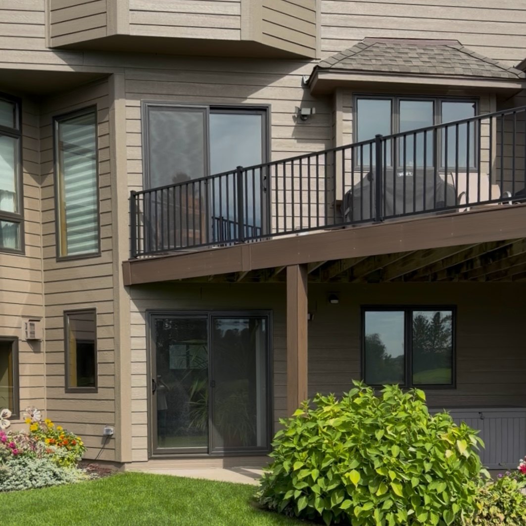 Rear balcony railing and patio doors on tan Siding