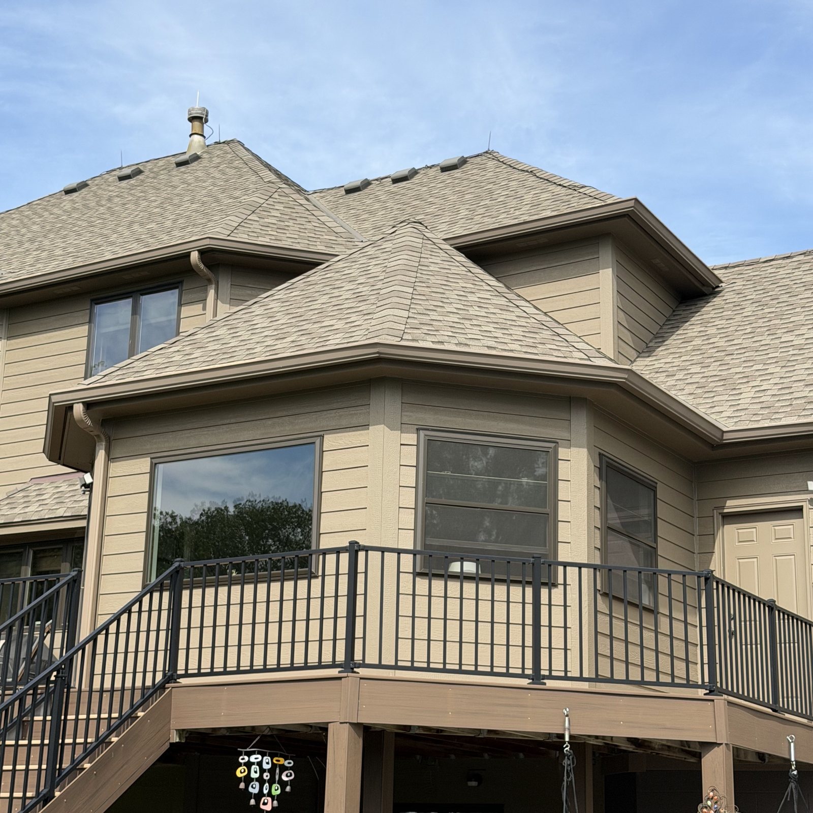 Upper bay window and deck railing on a tan-sided home
