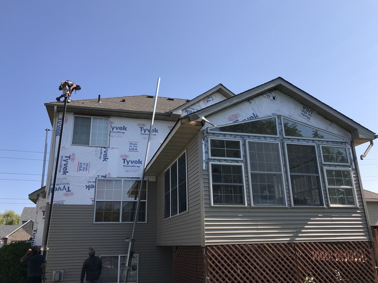 Two-story home mid re-side with house wrap on the walls and a sunroom off the back