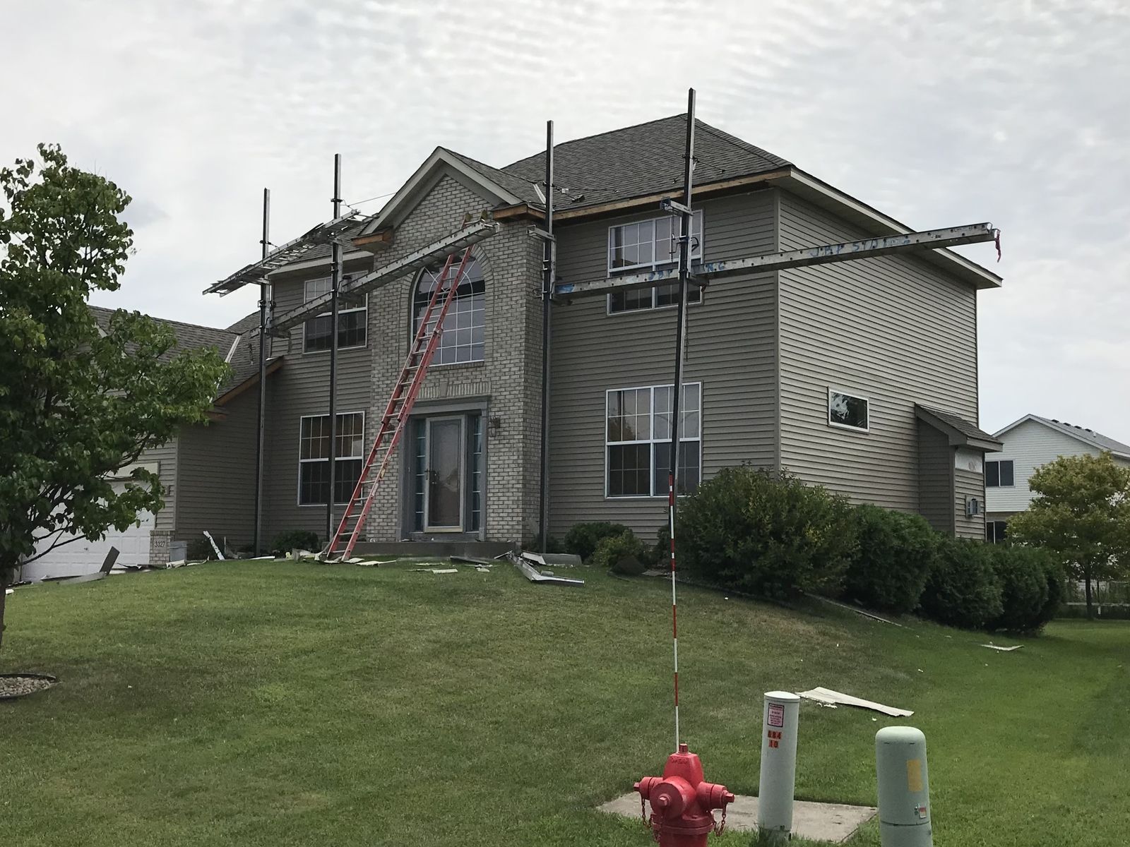 Two-story home with roof staging and ladders up during a re-roof