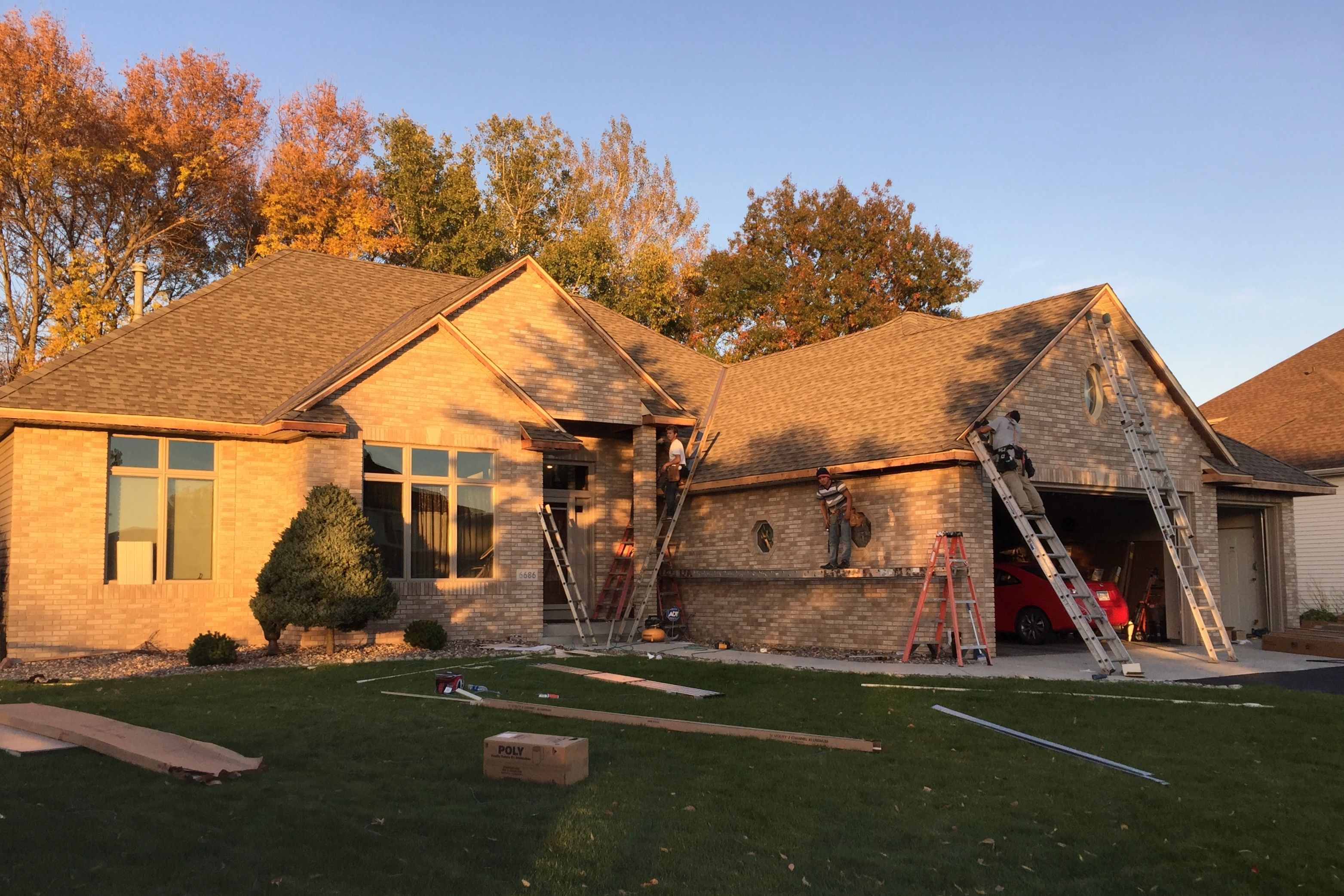 Brick ranch at golden hour with the crew on ladders replacing Soffit, Fascia, and trim