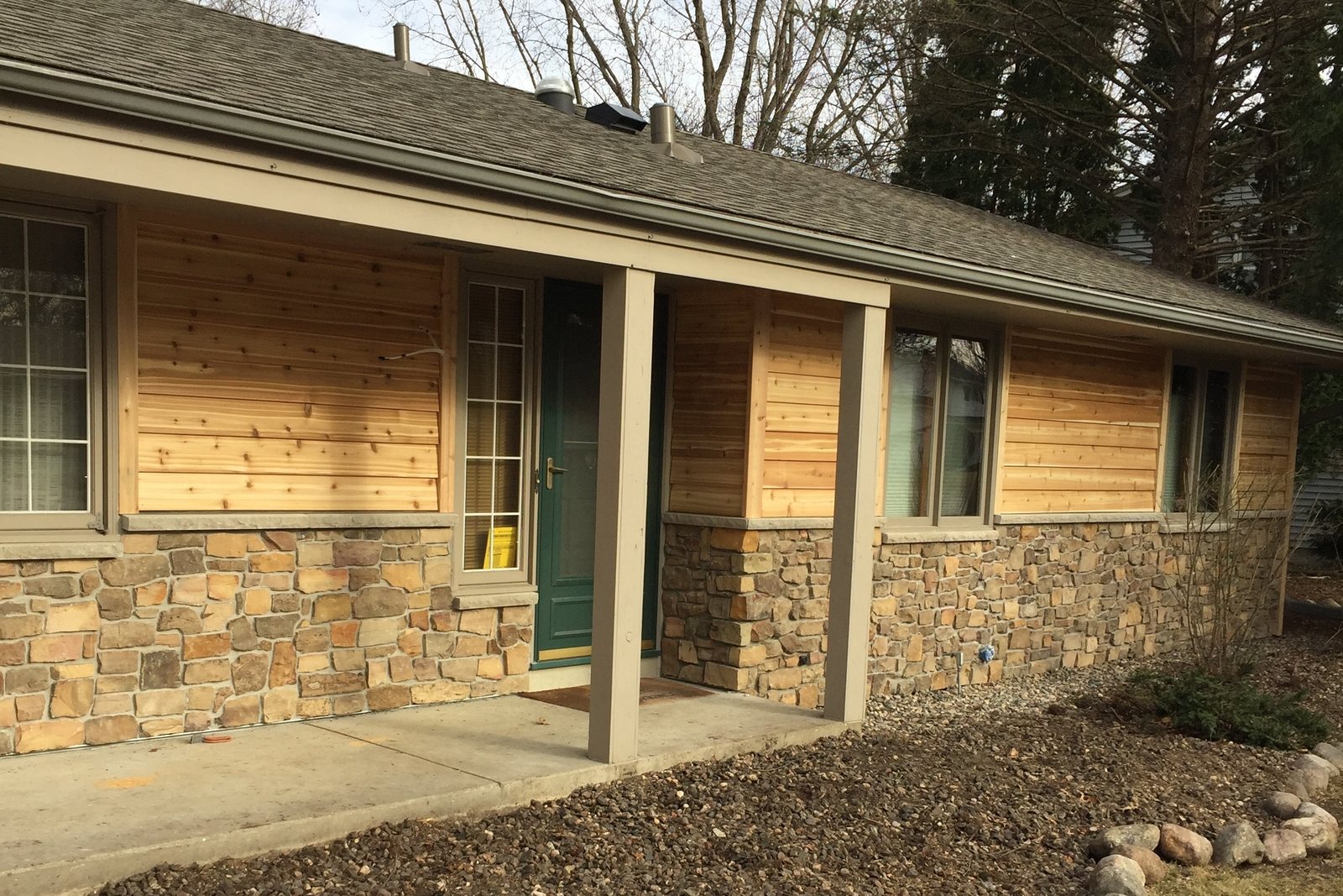 Natural cedar lap Siding above a stone base on a ranch home