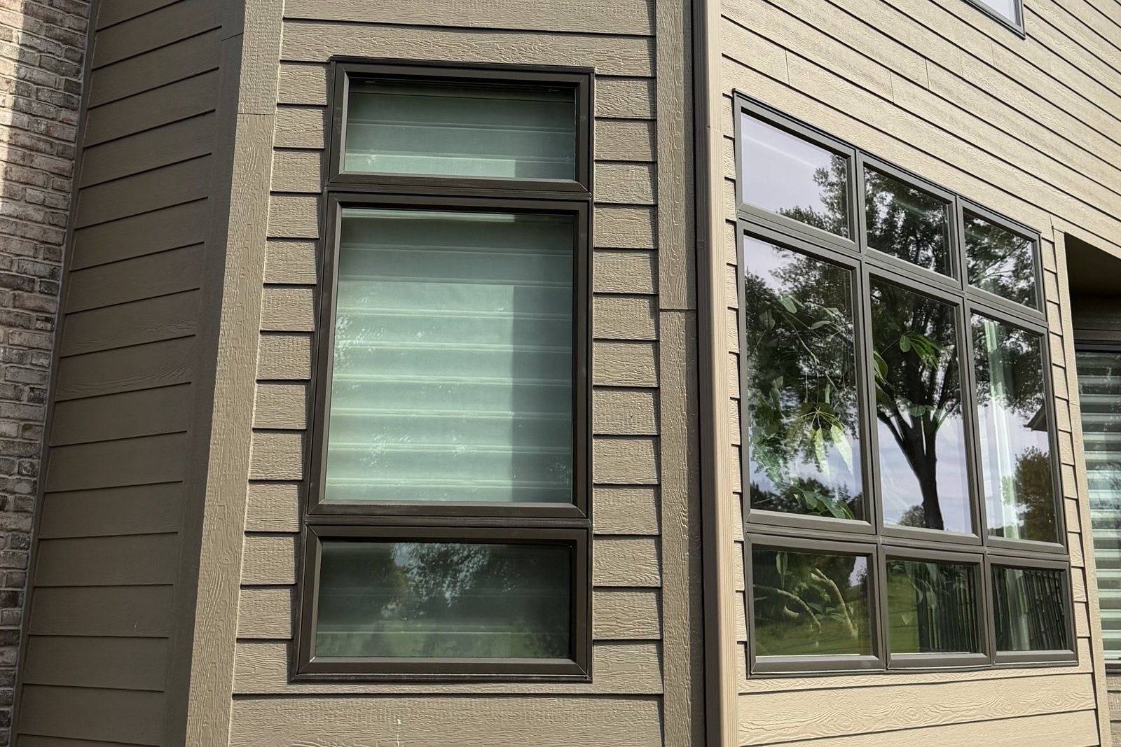 Trim boards framing stacked Windows and a corner on tan lap Siding
