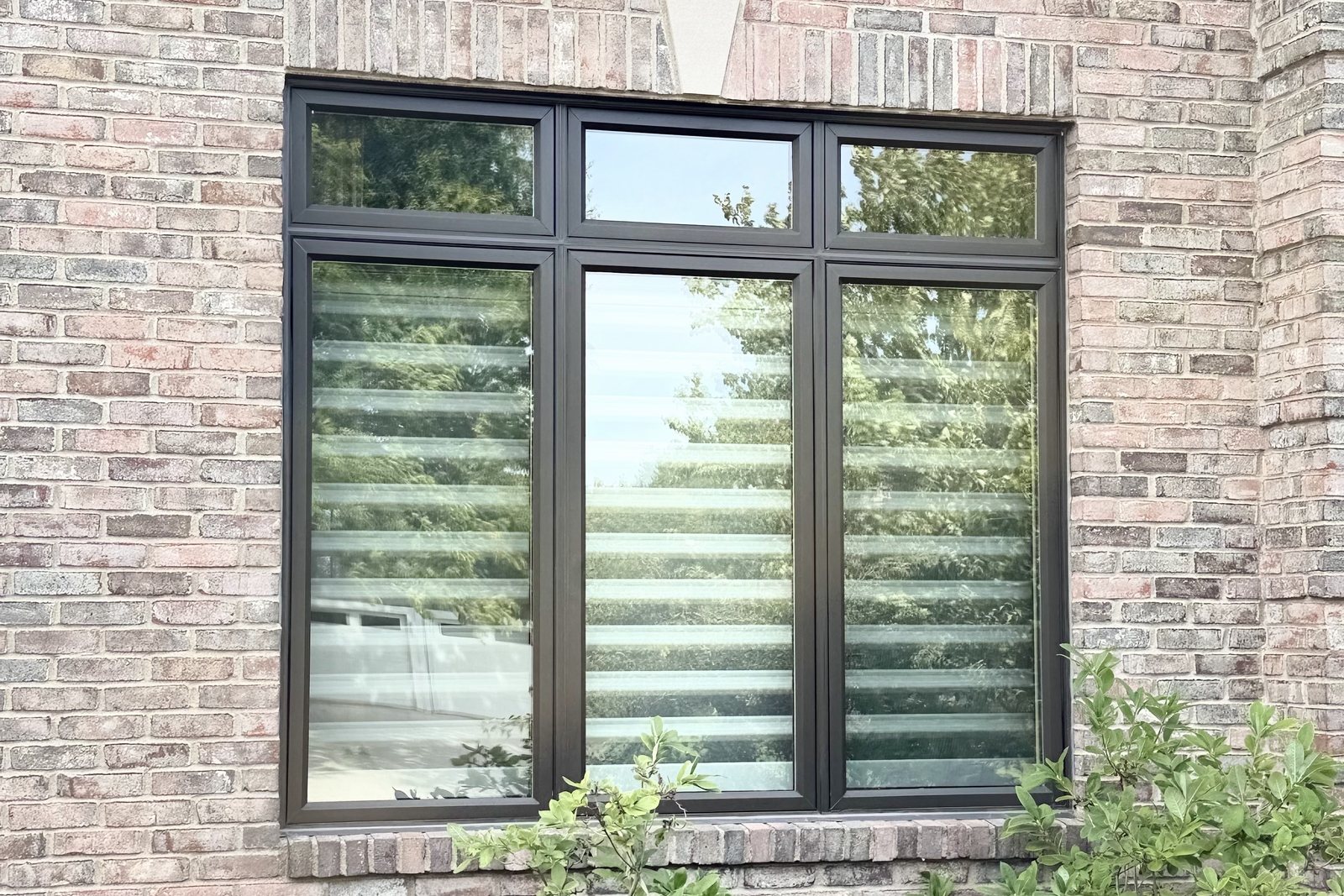 Three large Windows with smaller Windows above, set into a brick wall