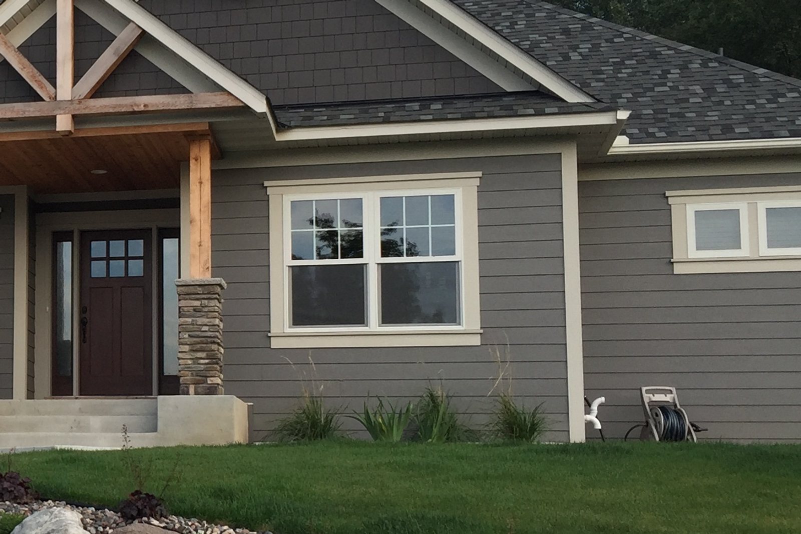 Pair of double-hung Windows with grids in the upper sash on gray lap Siding
