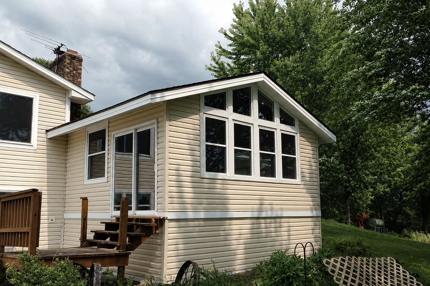 Three-season room addition lined with new Windows under a gable